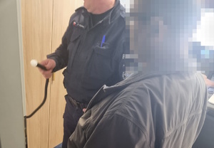 na zdjęciu policjant i mężczyzna badany alkomatem