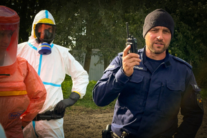 Zdjęcie przedstawiające rozmawiającego przez radio policjanta