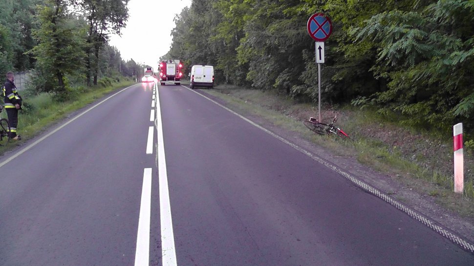 zdjęcie przedstawia drogę, na której widać wóz strażacki i samochody. W rowie leży rower
