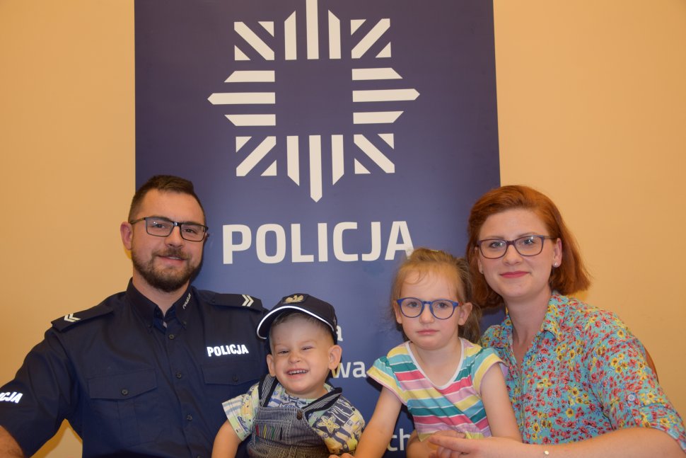 Na zdjęciu siedzi policjant wraz z żoną i swoimi dziećmi chłopczykiem i dziewczynką