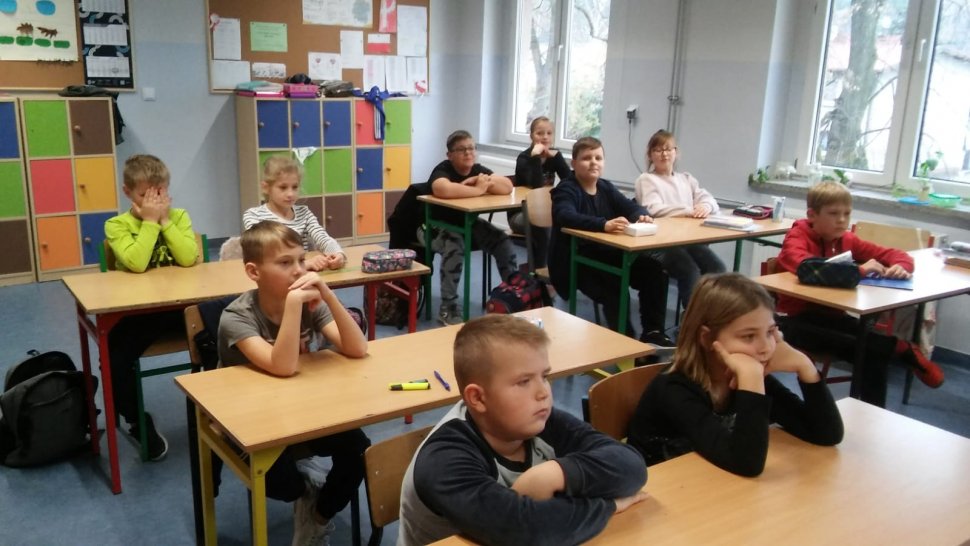 na zdjęciu widać szkolną klasę, w której uczniowie siedzą w ławkach