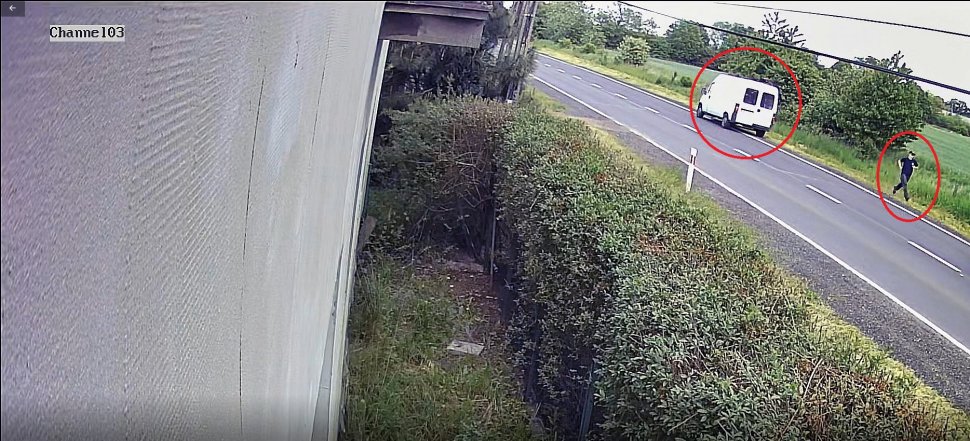 Na zdjęciu widać drogę, na której znajduje się zaparkowany biały bus. Nieopodal biegnie jego kierowca. Samochód oraz sylwetka mężczyzny, dla wyróżnienia zostały otoczone czerwonym kołem. 