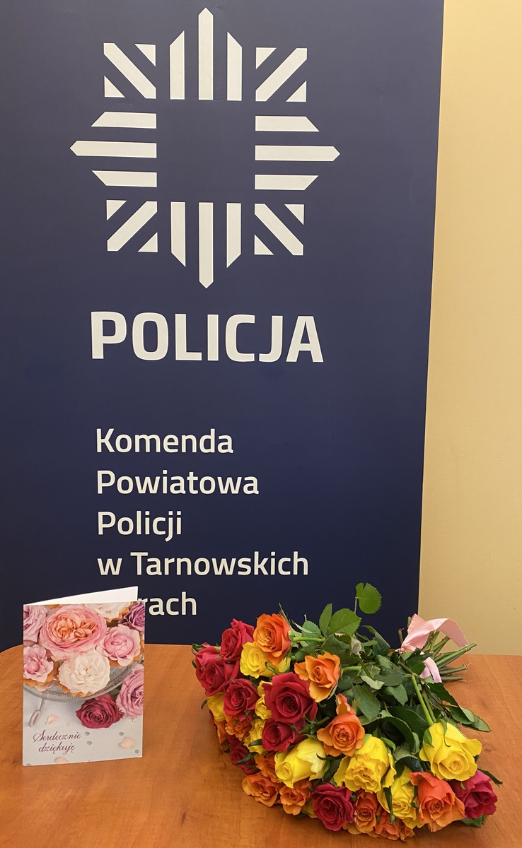 kwiaty i kartka na tle baneru z napisem policj