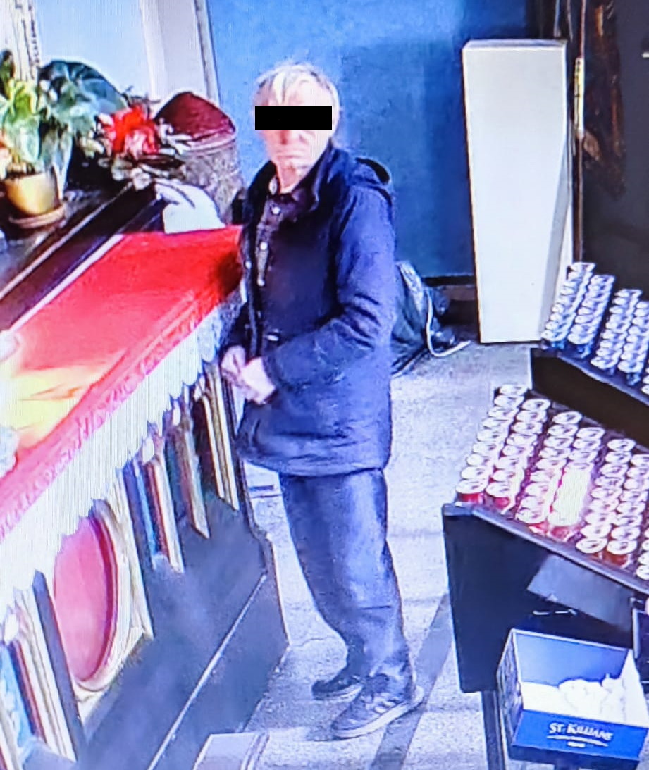 na zdjęciu mężczyzna ubrany na ciemno, włosy siwe, stoi w pomieszczeniu przy ołtarzu