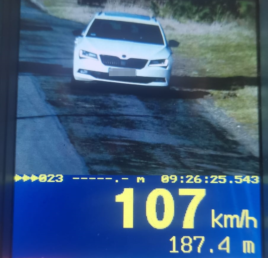 na zdjęciu ekran policyjnego urządzenia do pomiaru prędkości, na którym widać biały samochód oraz pomiar wskazujący prędkość 107 kilometrów na godzinę