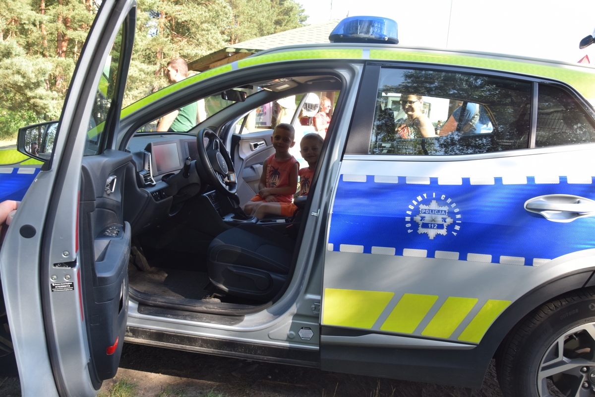 Na zdjęciu widoczni uczestnicy pikniku, radiowóz i motocykle