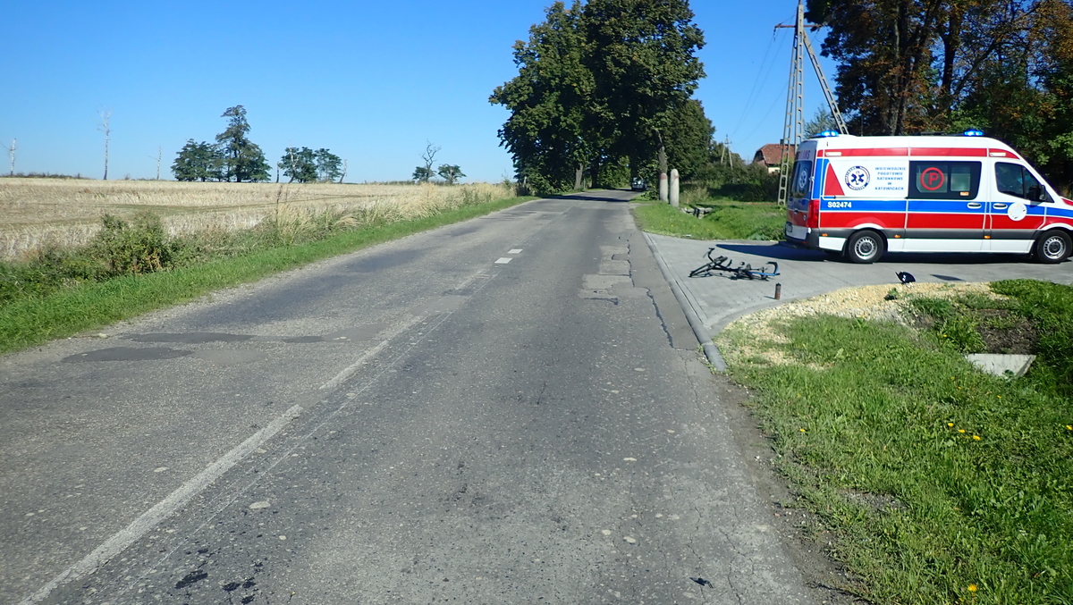 na zdjęciu odcinek drogi, na którym doszło do wypadku, obok zaparkowana karetka pogotowia i leżący obok rower