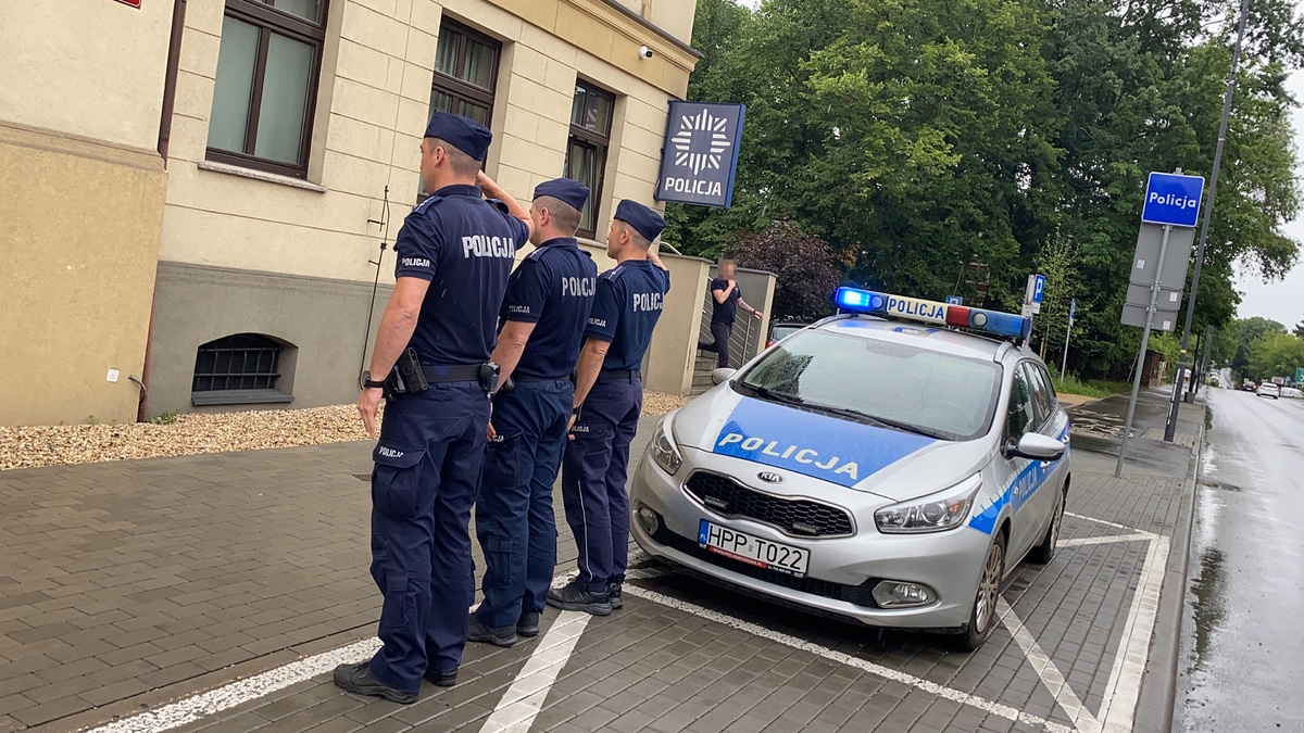 na zdjęciu policjanci przy radiowozie przed budynkiem komendy w trakcie oddawania honoru 
