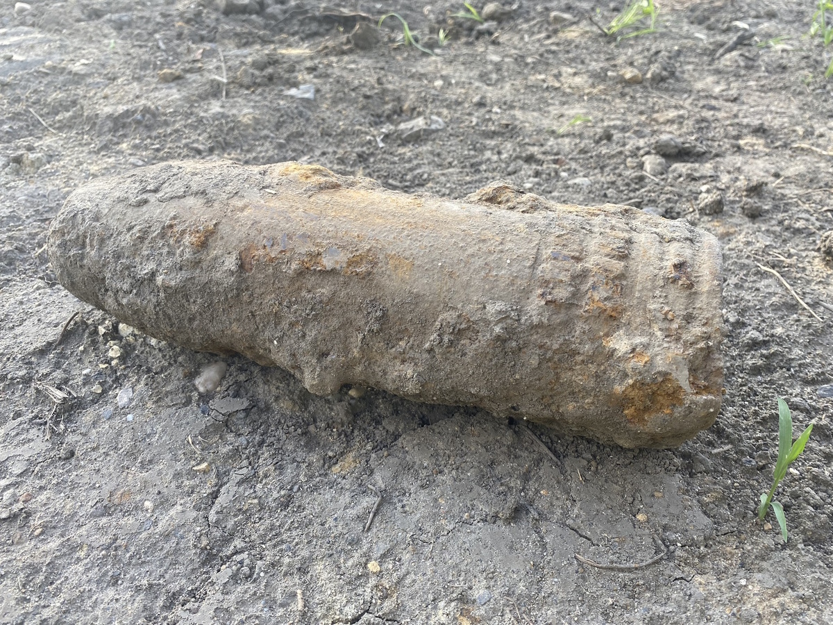 na zdjęciu zabrudzony ziemią pocisk leżący na podłożu