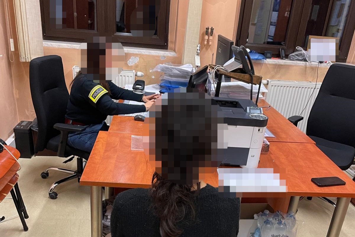 na zdjęciu nieletnia przy biurku, za którym siedzi policjantka z opaską na ramieniu 