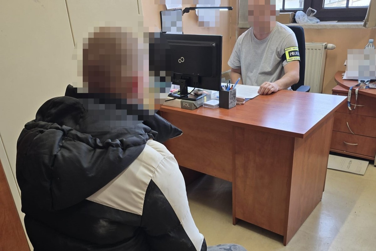 na zdjęciu policjant przy biurku, a przed nim zatrzymany