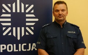 na zdjęciu dzielnicowy Tobor przy banerze z napisem policja