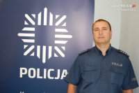 na zdjęciu dzielnicowy Frączek przy banerze z napisem policja