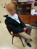 mężczyzna z zamazaną twarzą siedzący na krześle w biurze w budynku komendy w Tarnowskich Górach