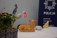 Zdjęcie przedstawia stroik świąteczny. W tle widać policyjny baner