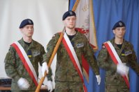 Zdjęcie przedstawia trzech uczniów szkoły, którzy niosą sztandar