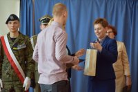 Zdjęcie przedstawia przedstawicielkę PLK wręczającą uczniowi upominek