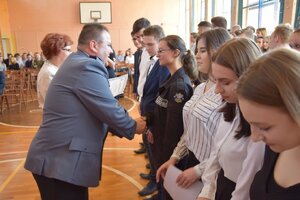 zdjęcie przedstawia Komendanta Policji, który gratuluje uczniom ukończenia szkoły.