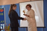Zdjęcie przedstawia dyrektora szkoły oraz uczennicę odbierającą statuetkę