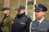 Zdjęcie przedstawia wartę honorową pod tablicą upamiętniającą pomordowanych z Kozielska, Ostaszkowa, Starobielska i innych obozów, którą pełnili tarnogórscy policjanci wraz z żołnierzami oraz funkcjonariuszami straży więziennej.