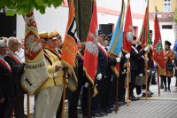 Zdjęcie przedstawia grupę osób trzymających sztandary.