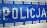 zdjęcie przedstawia bok radiowozu i napis POLICJA