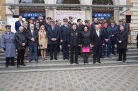 zdjęcie przedstawia grupę osób stojących przed dworcem kolejowym. Wśród nich znajdują się  ministrowie RP, europosłowie, posłowie na Sejm RP oraz samorządowcy. Jest również  Pierwszy Zastępca Komendanta Powiatowego Policji  w Tarnowskich Górach podinsp. Sławomir Bylicki.