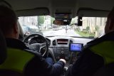 zdjęcie przedstawia dwóch policjantów siedzących w pojeździe służbowym.
