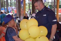 Na zdjęciu widać  policjanta asp. szt. Adama Cichowskiego oraz chłopca trzymającego w ręku żółte balony