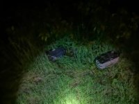 Na fotografii widać zarośla. Na trawie leżą  dwa akumulatory
