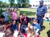 na fotografii widać dzielnicowego z Tworoga oraz grupę dzieci siedzących wokół strażaka.