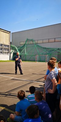 Policjant trzymający mikrofon, przeprowadza prelekcje z dziećmi