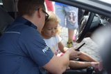 policjant w radiowozie rozmawia z dzieckiem podczas pikniku