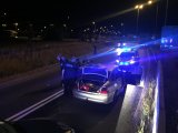 Na zdjęciu widać policyjne radiowozy z włączonymi sygnałami świetlnymi oraz inny zatrzymany przez policjantów samochód osobowy. Obok niego, znajdują się policjanci.