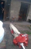 na zdjęciu widać złożony, leżący na ziemi parasol ogrodowy. W tle fotografii widać drzwi do pomieszczeń gospodarczych oraz stojącego w nich policjanta