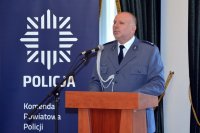 Na fotografii widać stojącego przy mównicy Komendanta Powiatowego Policji w Tarnowskich Górach mł. insp. Krzysztofa Hajdę. Z lewej strony fotografii, w tle widać policyjny baner.