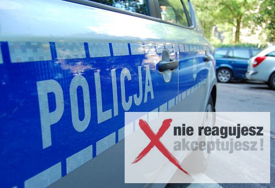 Na zdjęciu widać bok policyjnego radiowozu z napisem POLICJA. Z prawej strony fotografii widać znak X i napis nie reagujesz akceptujesz!