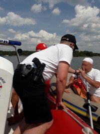 Na fotografii widać policjanta, który wykonuje badanie stanu trzeźwości u mężczyzny, który pływa kajakiem