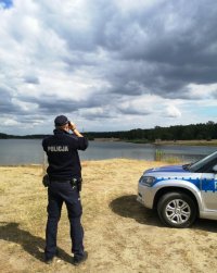 na fotografii widać policjanta obserwującego zbiornik wodny