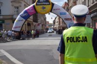 na fotografii widać odwróconego tyłem policjanta. W tle widać start Tour de Pologne oraz stojących po bokach ulicy  tłum ludzi