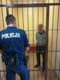 mężczyzna za policyjnymi kratami w obecności policjanta