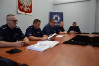 Na fotografii widać salę odpraw. Przy stole siedzą policjanci oraz Pierwszy Zastępca Komendanta Powiatowego Policji w Tarnowskich Górach podinsp. Sławomir Bylicki