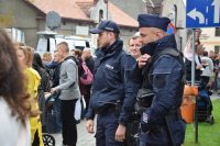 Na fotografii widać dwóch policjantów, którzy stoją pośród tłumu ludzi.