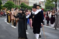 Na fotografii widać idących ulicą uczestników pochodu. Przebrani są za historyczne postacie. Po obydwu stronach ulicy znajduje się tłum ludzi.