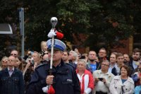 Na fotografii widać policjanta. W tle zdjęcia, z tyłu za policjantem znajduje się tłum ludzi.
