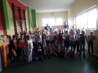 Na fotografii widać grupę dzieci, które unoszą do góry odblaskowe zawieszki. Wśród nich znajdują się dwaj policjanci.