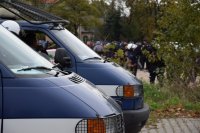 Na fotografii widać dwa policyjne radiowozy. W tle fotografii widać tłum ludzi.