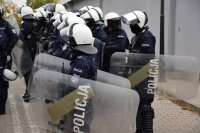 Na fotografii widać kilku policjantów, którzy są ubrani w kamizelki i hełmy.