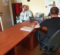 Na fotografii widać dwóch mężczyzn, którzy siedzą przy biurku.