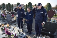 Na fotografii widać cmentarz, na którym znajduje się Komendant Powiatowy Policji w Tarnowskich Górach insp. Krzysztof Hajda, Zastępca Naczelnika Prewencji Zbisław Pawłowski oraz kapelan policji diecezji gliwickiej ks. Joachim Gondro. Policjanci oddają honor.